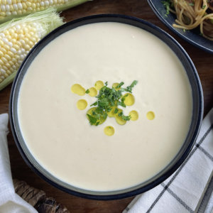 Corn potage in a black bowl with ears of corn and pasta