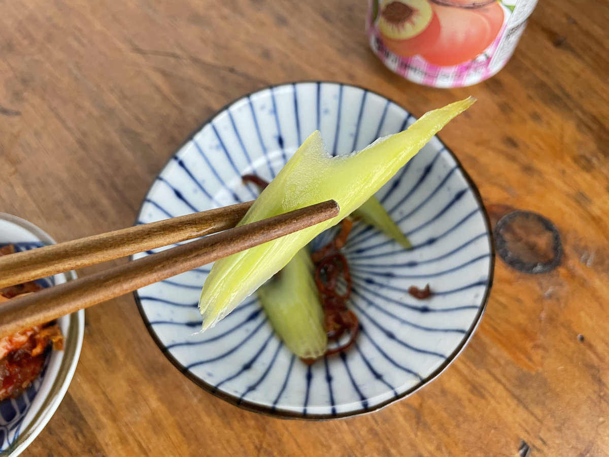 Japanese Pickled Celery Asazuke in chopsticks with a small bowl in background