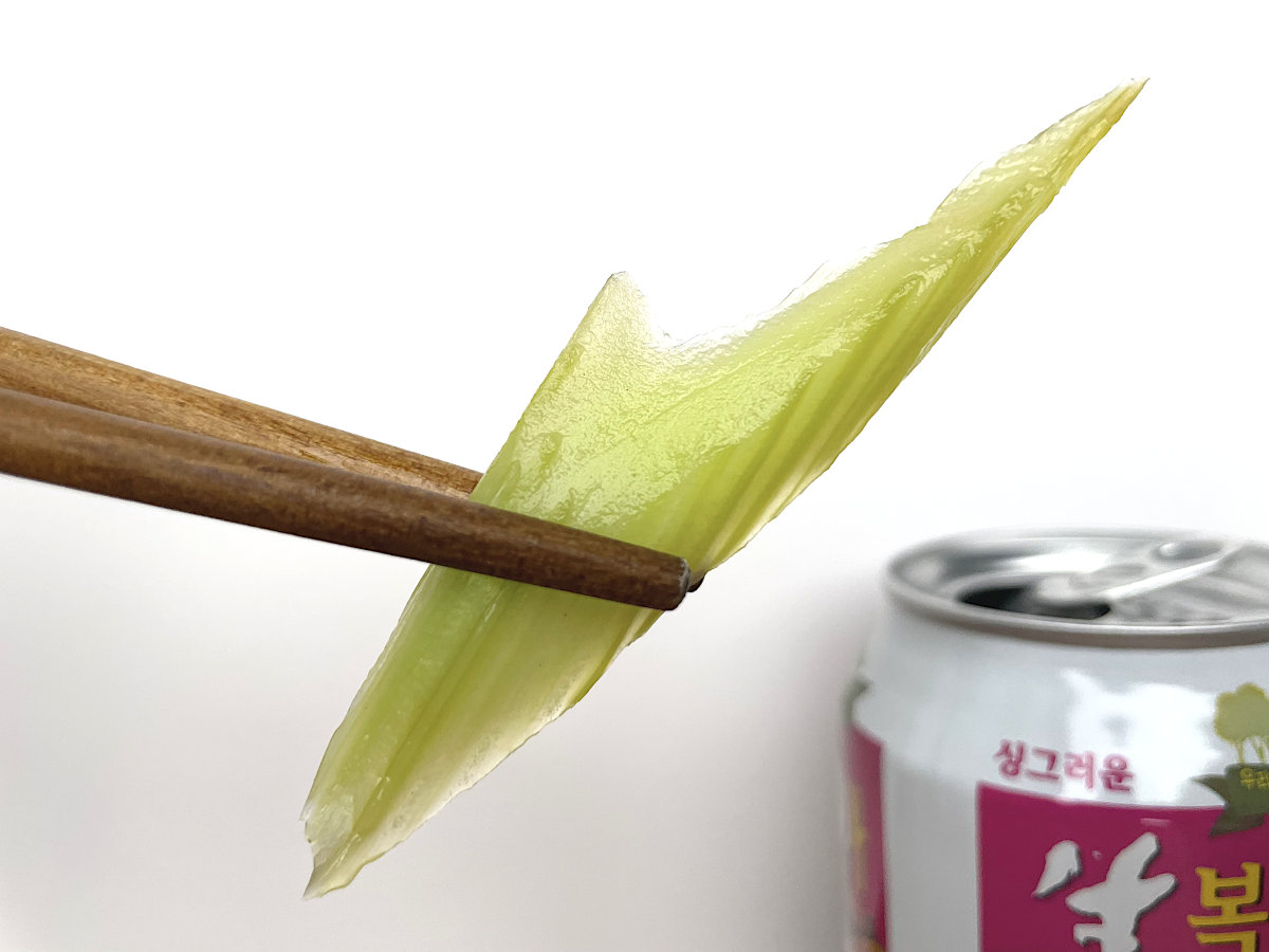 Japanese Pickled Celery Asazuke in chopsticks with Korean peach drink in background