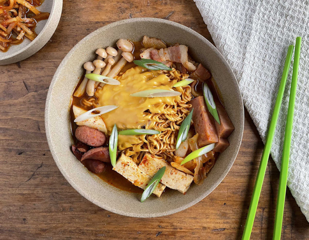 Korean Army Stew with green chopsticks and moochae in background