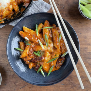 Rose tteokbokki without fish cakes in a bowl and cast iron pan