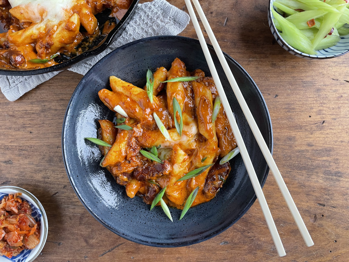 Rose tteokbokki without fish cakes in a bowl and cast iron pan