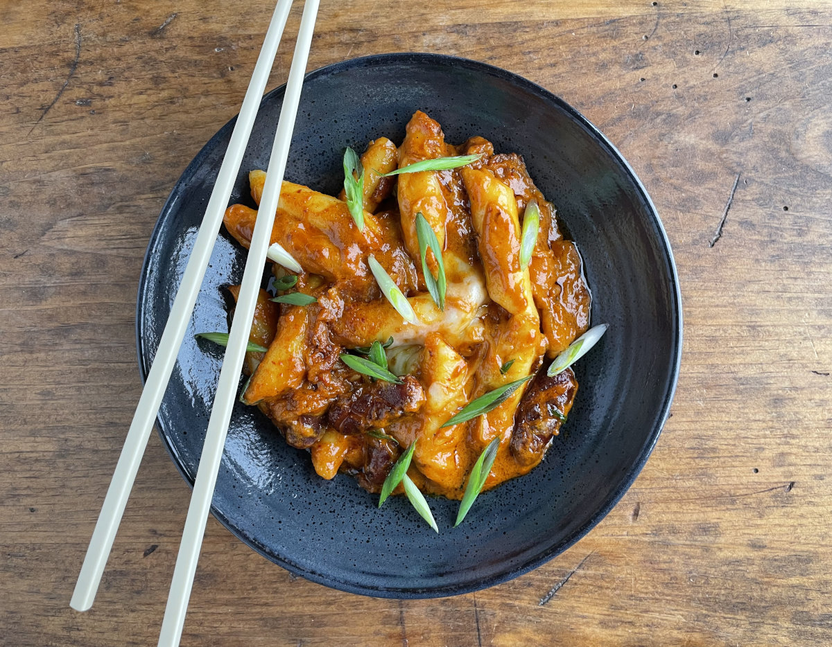 Rose tteokbokki without fish cakes in a black bowl with chopsticks