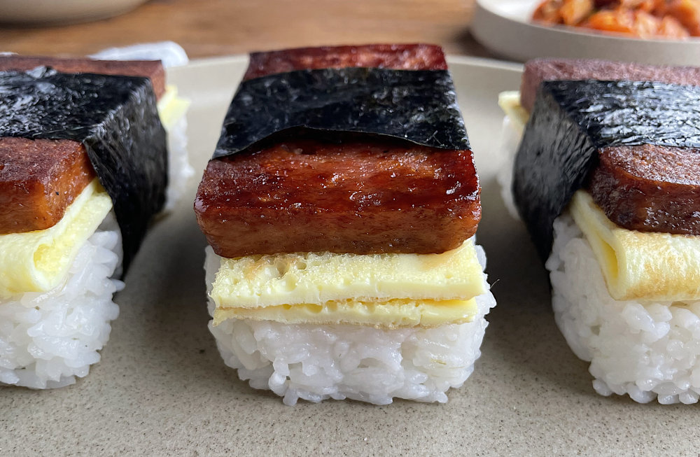 Spam musubi from front with kimchi in background