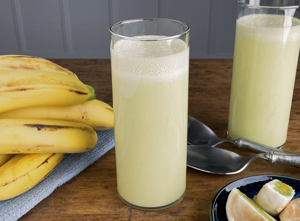 Two glasses banana milk with a bunch of fresh bananas