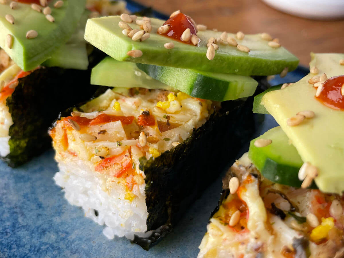sushi bake wrapped in seaweed and topped with cucumber and avocado