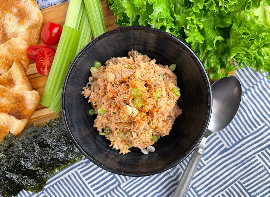 Gochujang tuna salad in a black bowl with vegetables on the side