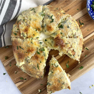 Korean Cream Cheese Garlic Bread with a piece cut out on cutting board